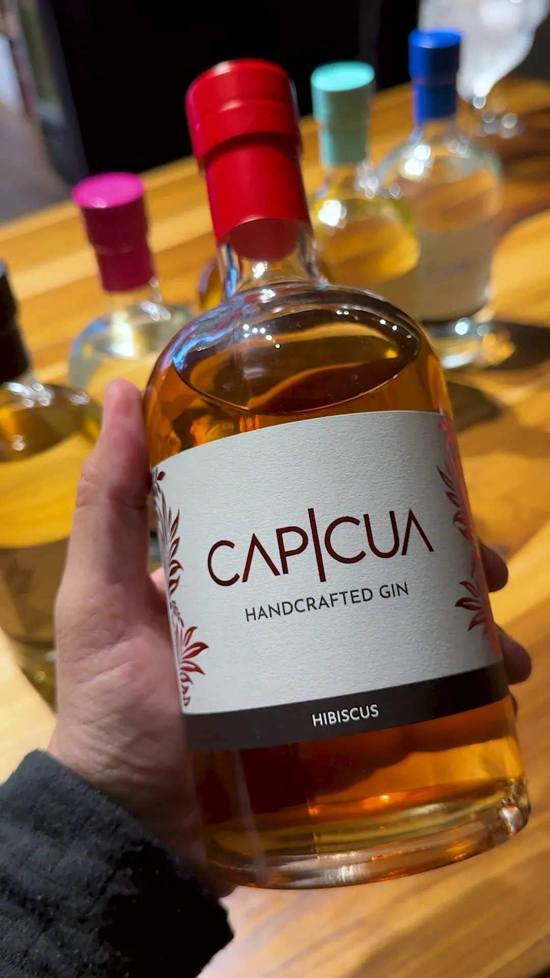 Botella de Hibiscus CAPICÚA sostenida frente a la barra