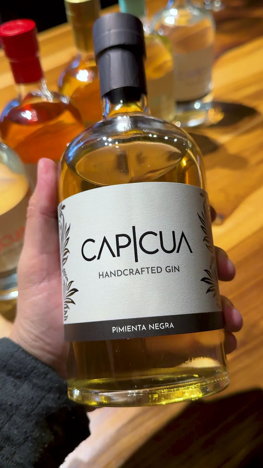 Botella de Pimienta Negra CAPICÚA sostenida frente a la barra