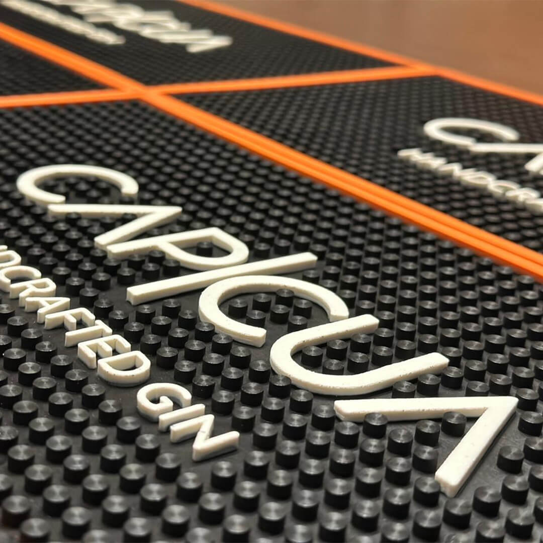 Detalle de varios barmats CAPICÚA negros con borde naranja