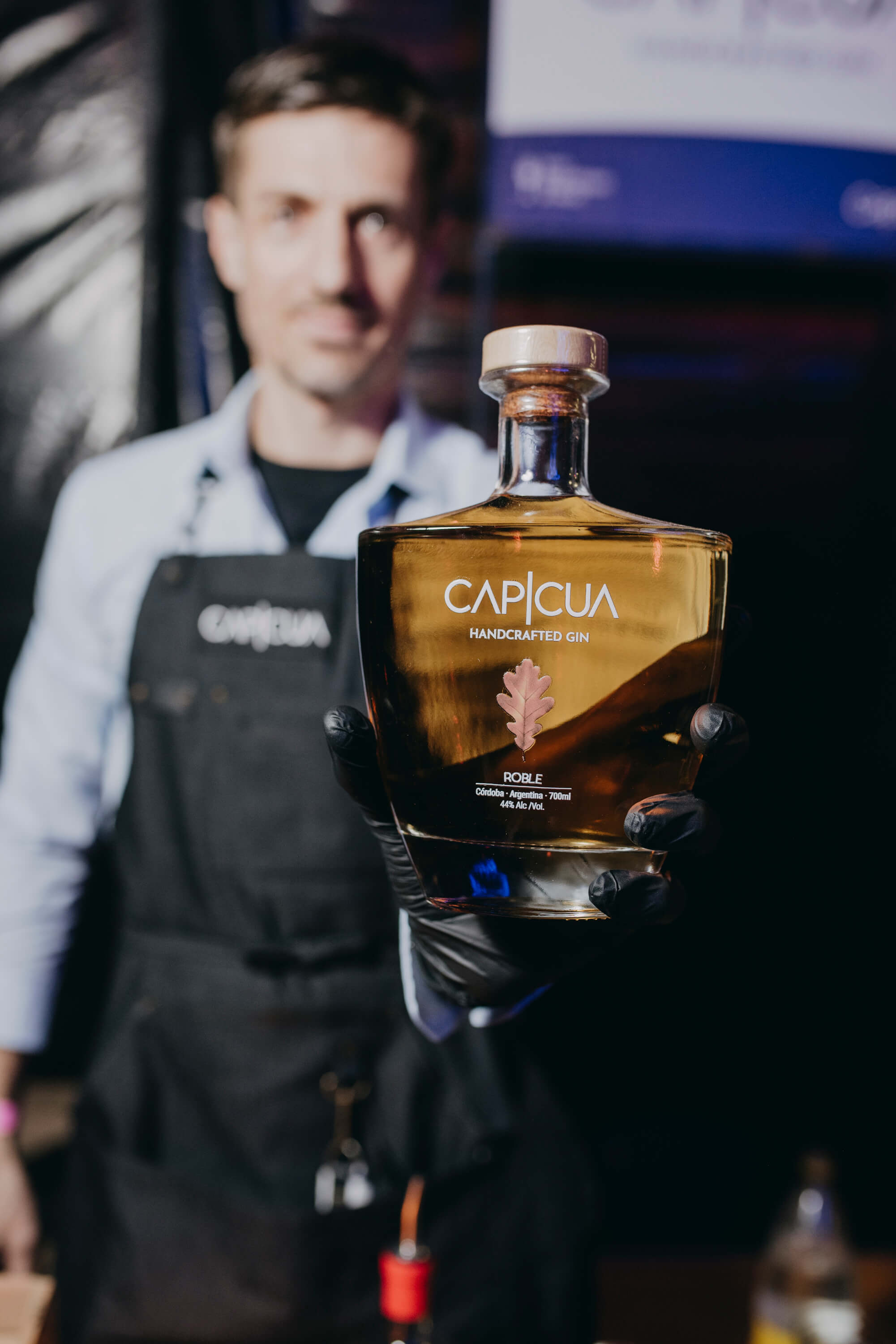 Integrante del equipo sosteniendo una botella CAPICÚA Roble durante un evento