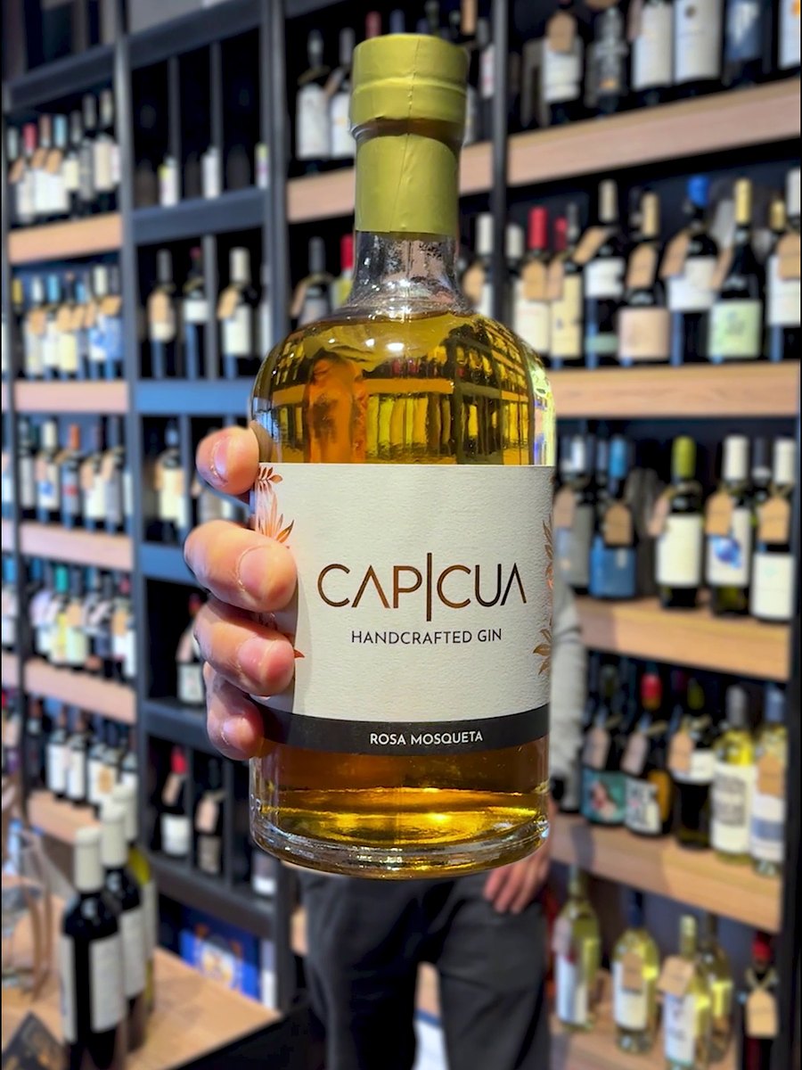 Persona eligiendo una botella CAPICÚA Rosa Mosqueta en una vinoteca
