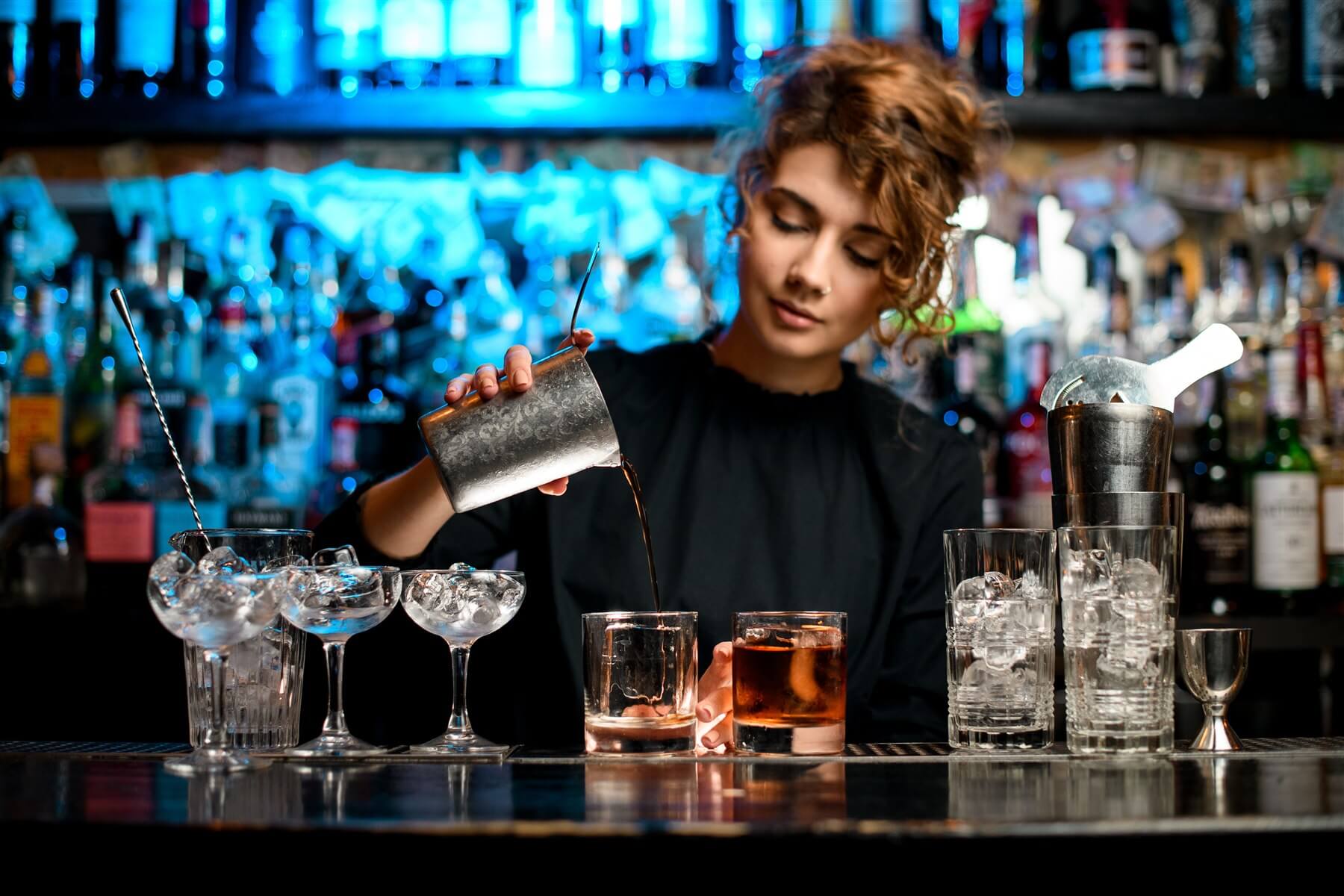 Barwoman preparando cócteles detrás de una barra