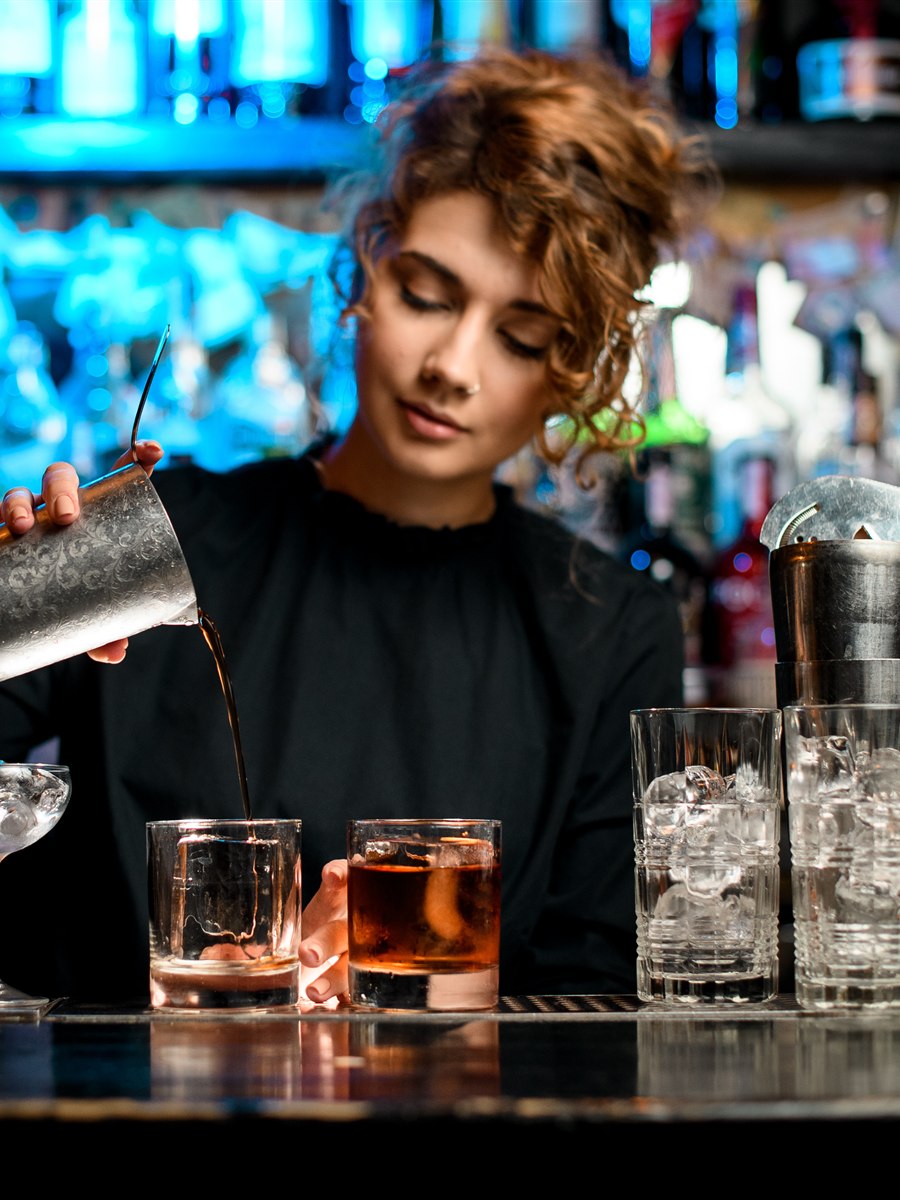 Barwoman preparando cócteles detrás de una barra